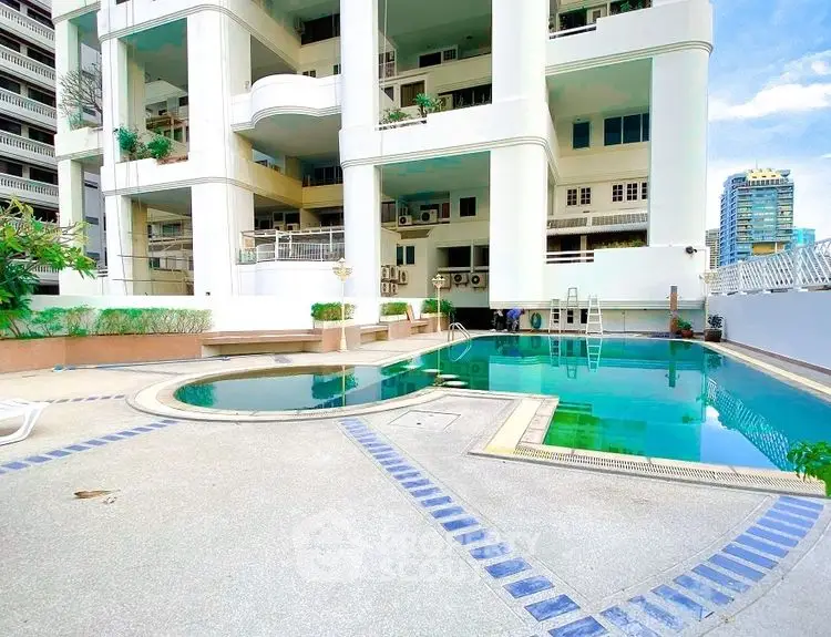 Luxurious residential building with modern pool and spacious deck area.