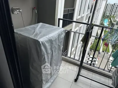 Compact balcony with washing machine and city view, ideal for urban living.