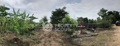 Expansive land with lush greenery and a rustic entrance gate, perfect for development.