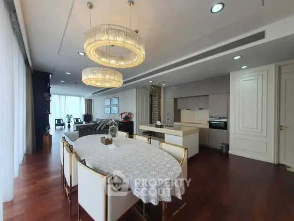 Luxurious open-plan living and dining area with elegant chandeliers and modern kitchen.