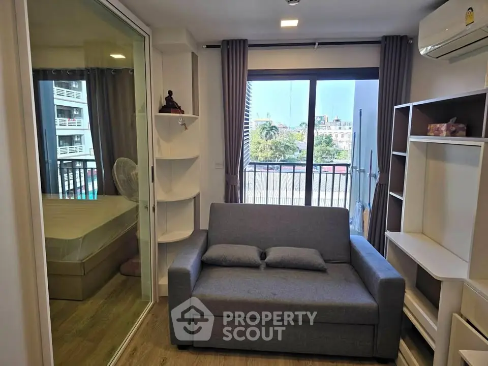 Modern living room with gray sofa, large window, and view of cityscape, perfect for urban living.