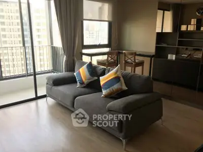 Modern living room with stylish sofa and city view balcony in high-rise apartment.