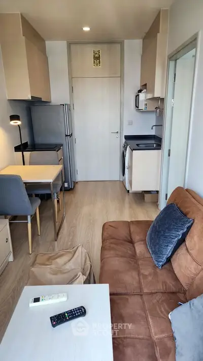Modern compact living room with kitchen, featuring cozy sofa and dining area in stylish apartment.