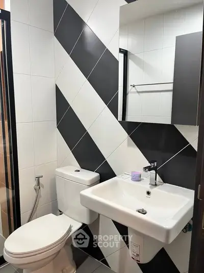 Modern bathroom with stylish black and white tiles and contemporary fixtures.