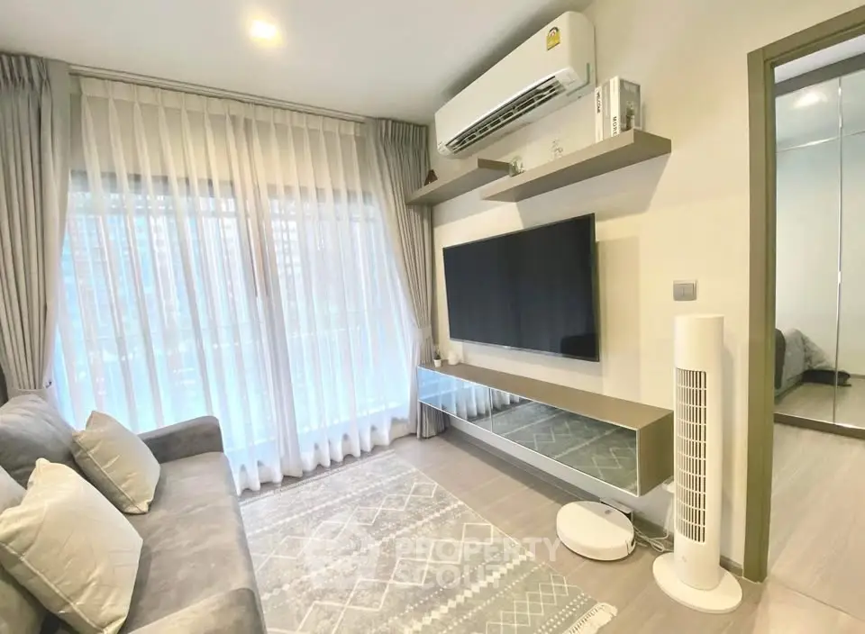 Modern living room with large TV, air conditioning, and stylish decor in a cozy apartment.