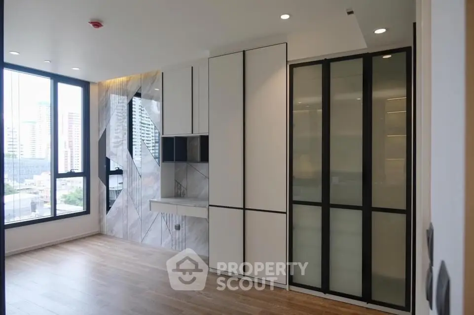 Modern minimalist apartment interior with large windows and sleek storage solutions.