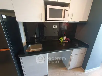 Modern kitchen with sleek black countertop and built-in microwave