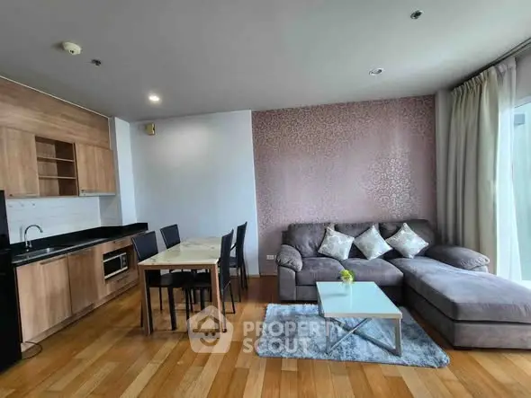 Modern living room with open kitchen, featuring stylish furniture and elegant decor.