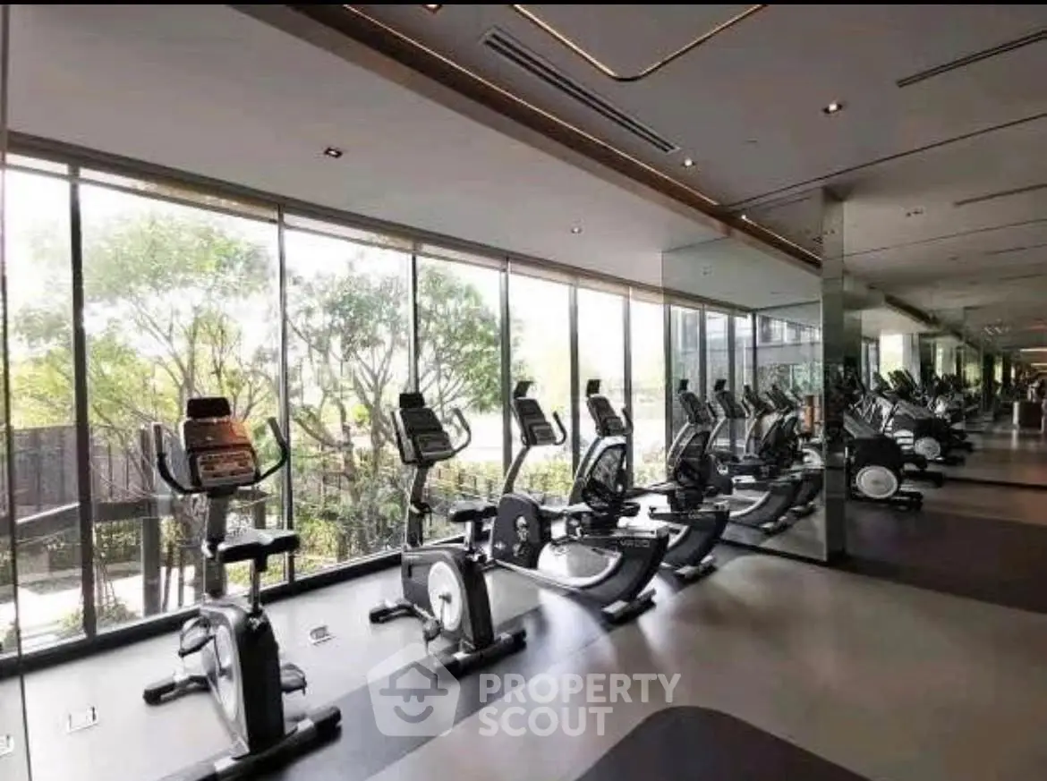 Modern gym with large windows and exercise equipment in luxury real estate.