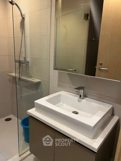 Modern bathroom with sleek sink and glass shower enclosure, perfect for contemporary living.