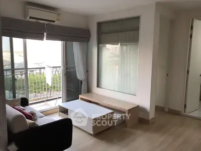 Modern living room with balcony view, featuring sleek furniture and natural light.