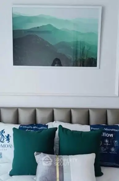 Stylish bedroom with elegant decor and plush pillows, featuring a serene mountain landscape artwork.