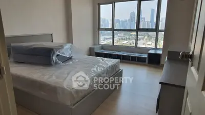 Spacious bedroom with large windows offering a panoramic city view, featuring a modern design and ample natural light.