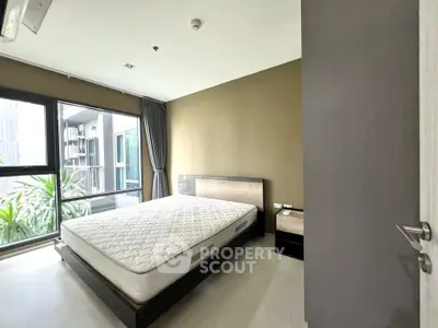 Spacious bedroom with large windows and modern furnishings in a stylish apartment.