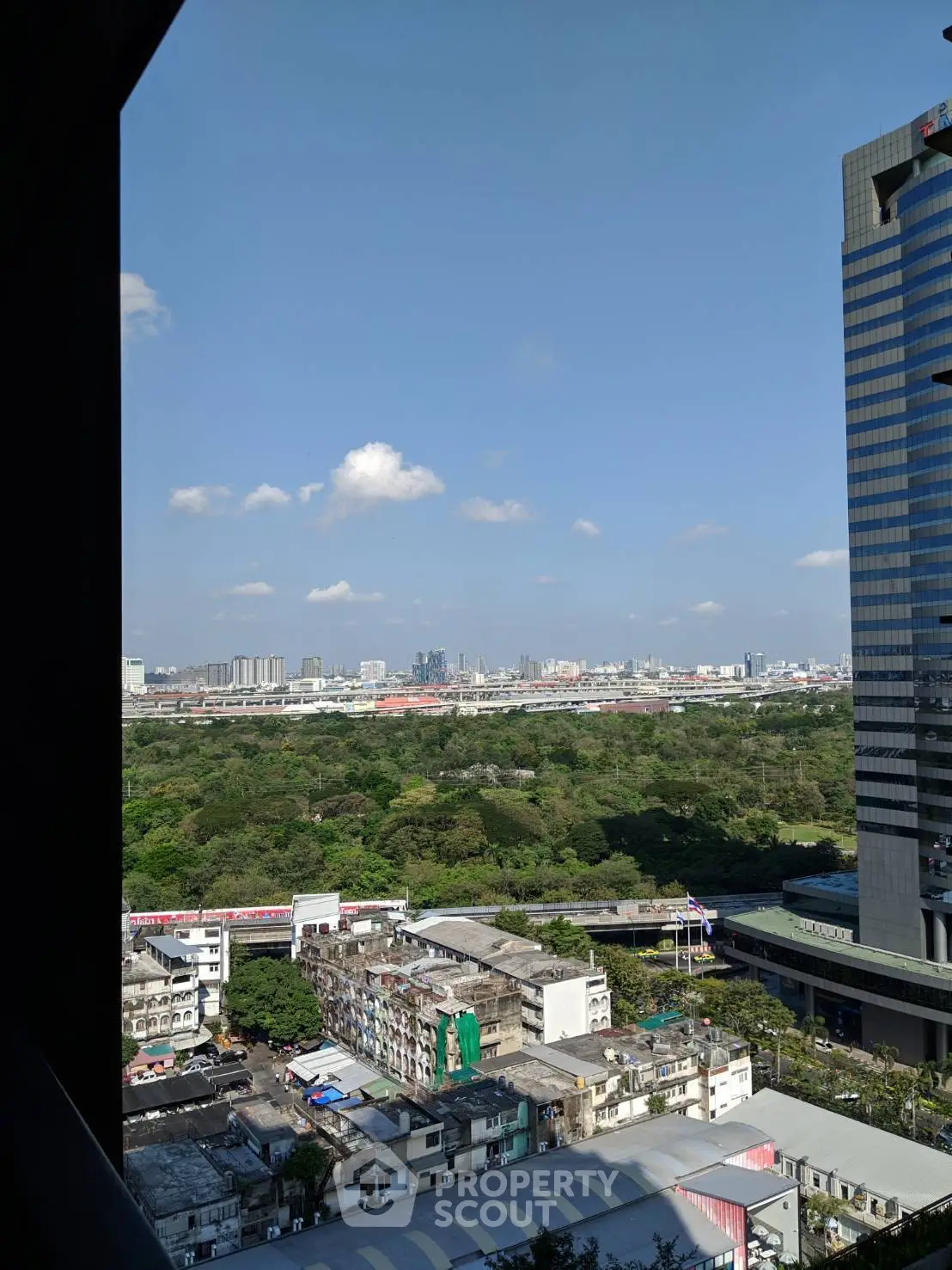 Stunning cityscape view from a high-rise building, showcasing urban skyline and greenery.
