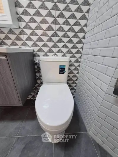 Modern bathroom with stylish geometric tiles and sleek toilet design.