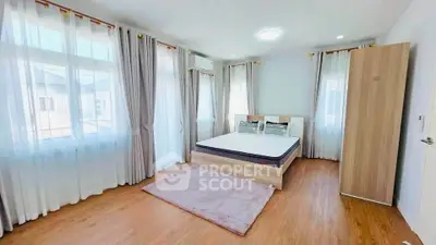Spacious bedroom with large windows and modern decor in a bright apartment.