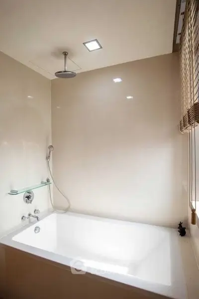 Modern bathroom with sleek bathtub and overhead shower, featuring minimalist design and natural light.