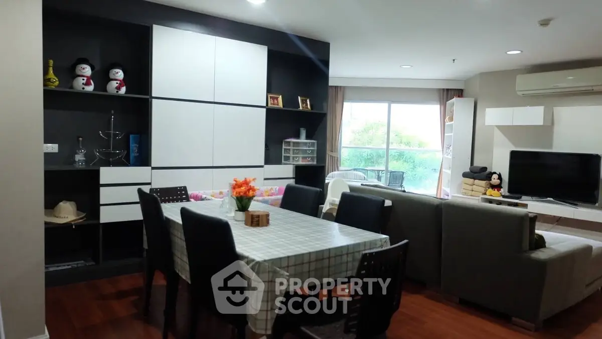 Spacious living room with dining area and modern decor, featuring large windows and stylish furniture.