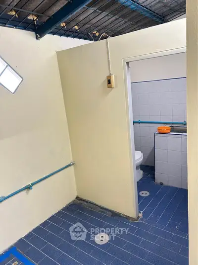 Compact bathroom with blue tiled floor and simple fixtures, ideal for small spaces.