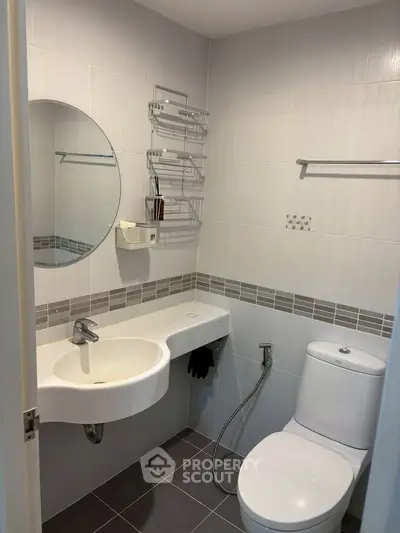 Modern bathroom with sleek fixtures and minimalist design, featuring a round mirror and contemporary tiling.