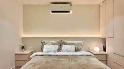 Modern bedroom with cozy lighting and built-in storage, featuring a comfortable bed and air conditioning.