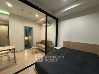 Modern studio apartment with glass partition, cozy living area, and stylish decor.