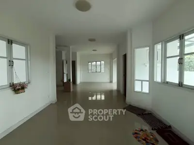 Spacious open-plan living area with large windows and glossy floors in a modern home.