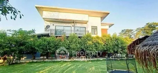 Modern two-story house with lush garden and spacious lawn, perfect for family living.