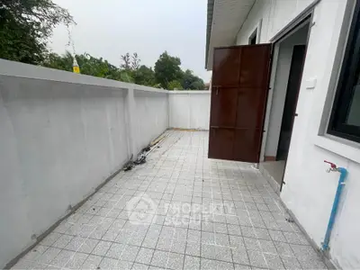 Spacious outdoor balcony with tiled flooring and garden view, perfect for relaxation.