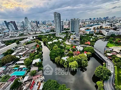 Stunning aerial view of urban skyline with lush greenery and river, showcasing modern high-rise buildings.