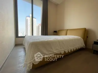 Modern bedroom with large window offering stunning city view in high-rise apartment.