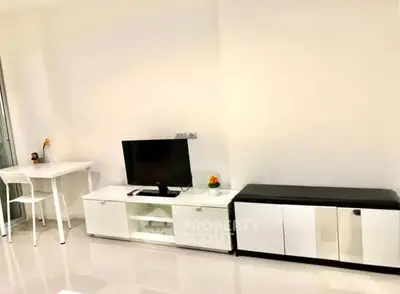 Modern living room with sleek white furniture and a flat-screen TV, perfect for urban living.
