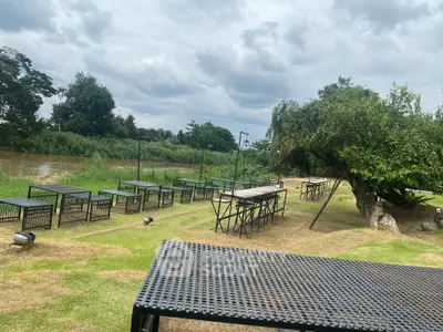 Scenic outdoor garden with tables by the riverside, perfect for relaxation.