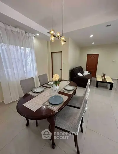 Elegant dining area with modern lighting and cozy living room setup