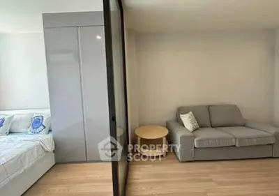 Modern studio apartment with cozy living area and stylish bedroom separated by glass partition.