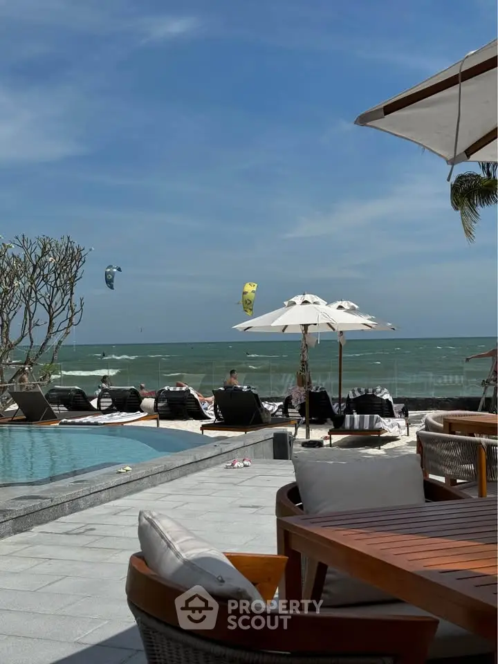 Luxurious beachfront pool area with ocean view and sun loungers, perfect for relaxation and leisure.