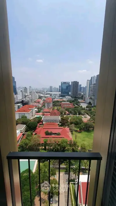Stunning cityscape view from a high-rise balcony overlooking urban skyline and lush greenery.