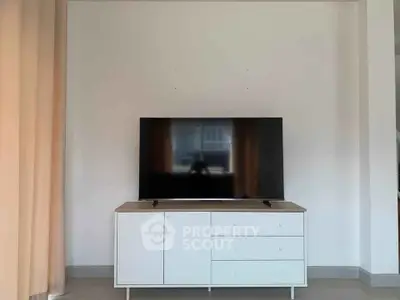 Modern living room with sleek TV stand and flat-screen TV, ideal for entertainment setup.