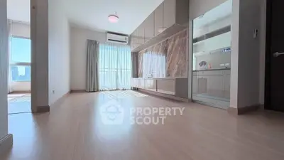 Spacious modern living room with large windows and sleek cabinetry, offering abundant natural light and city views.