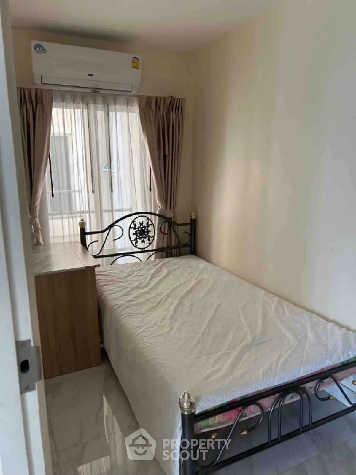 Cozy bedroom with metal bed frame and air conditioning, perfect for comfortable living.