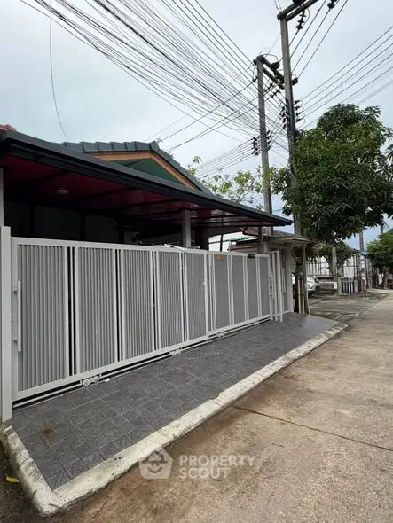 Modern residential property with gated entrance and paved driveway in a suburban neighborhood.