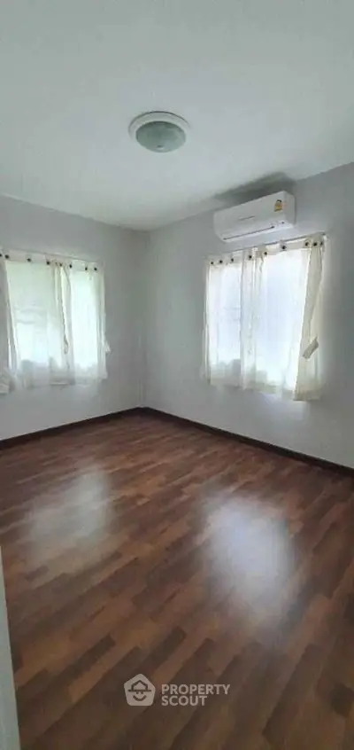 Spacious empty bedroom with wooden flooring and natural light