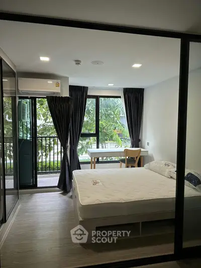 Modern bedroom with large windows and balcony view, featuring sleek design and natural light.