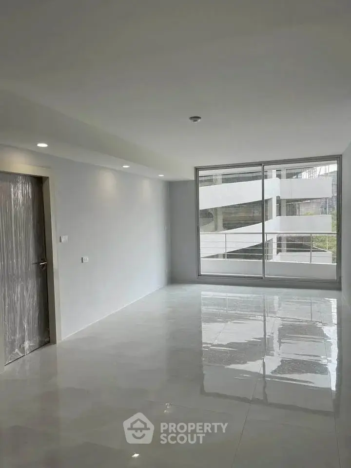 Spacious modern living room with large windows and glossy tiled floors.