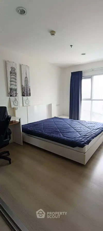Spacious bedroom with modern decor and large window offering natural light.