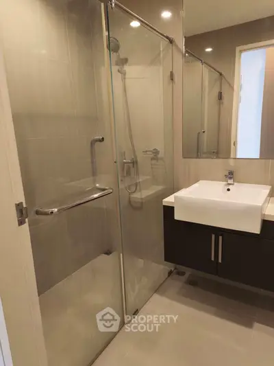 Modern bathroom with glass shower and sleek vanity in contemporary apartment.