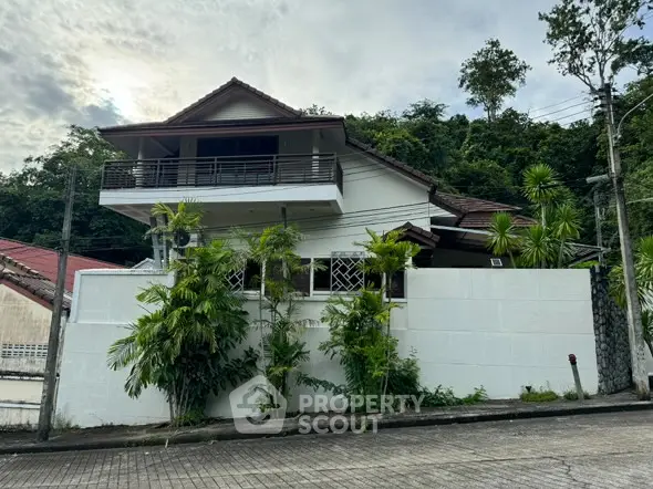 Charming two-story house with lush greenery and spacious balcony in serene neighborhood.