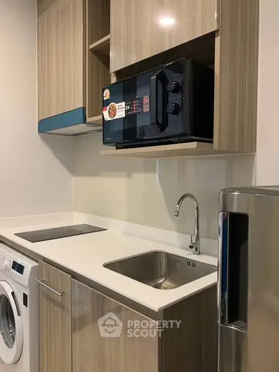 Modern kitchen with sleek cabinetry, built-in microwave, and washing machine.