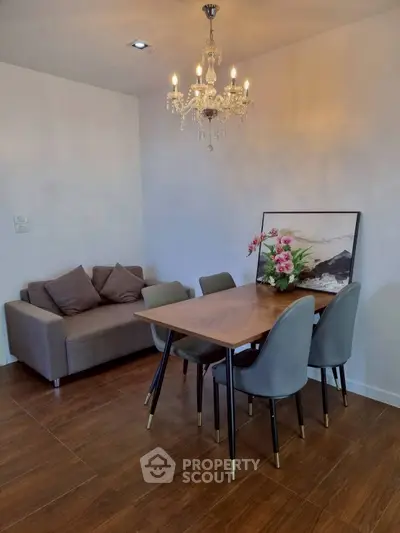 Elegant dining area with chandelier and modern furniture in a cozy apartment setting.